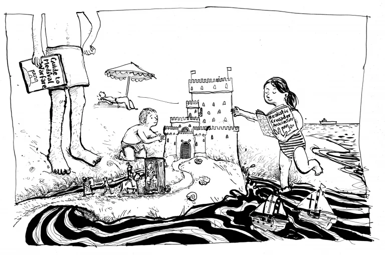 Children building a sandcastle on the beach beside sunbathers and a parasol