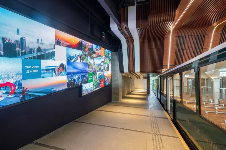 A curved wall of colourful photographs of Hong Kong inside the Peak Tram terminus
