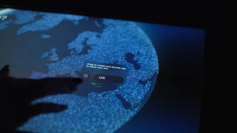 A visitor’s hand on an interactive globe projected onto a table, with a pop-up question to answer